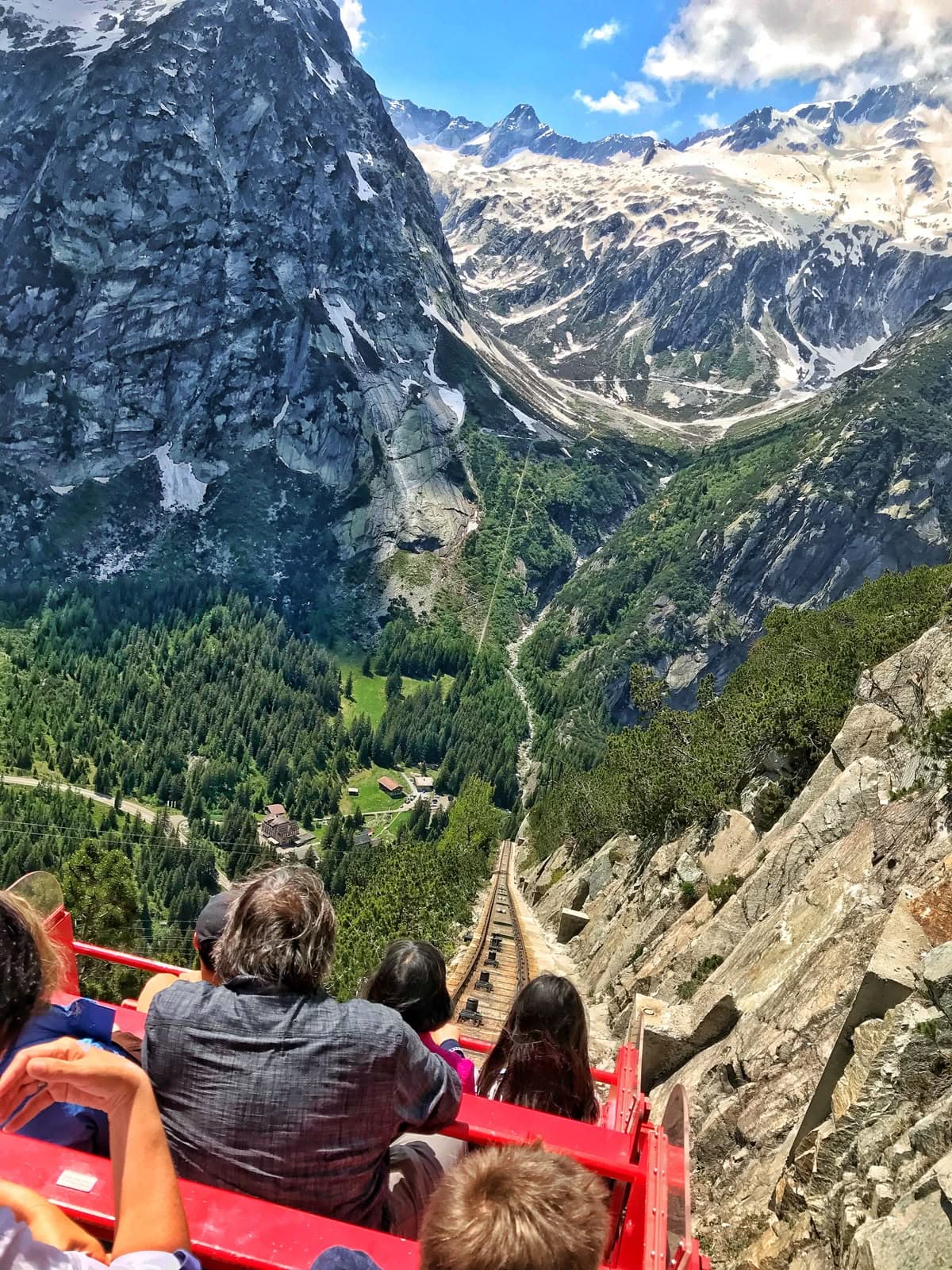 Red funicular descending into a dramatic alpine valley